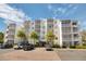 Condo building featuring a white facade, multiple balconies, and well-maintained landscaping with palm trees at 1100 Delaney Ave # F409, Orlando, FL 32806