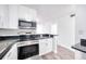 Updated kitchen with stainless steel appliances, white cabinetry, dark countertops, and stylish wood-look flooring at 1100 Delaney Ave # F409, Orlando, FL 32806