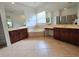 Bathroom featuring double vanities, a soaking tub, decorative mirrors, and neutral-toned tile flooring at 13413 Zori Ln, Windermere, FL 34786