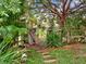 Landscaped backyard featuring a wooden gate, lush tropical plants, and stone pavers at 14540 Pointe East Trl, Clermont, FL 34711