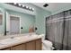Well-lit bathroom featuring a double sink vanity, shower with curtain, and refreshing color palette at 1735 Pine Ridge Dr, Davenport, FL 33896