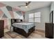 Bedroom featuring hardwood floors, light blue walls with a modern artistic accent wall, and white trim at 1735 Pine Ridge Dr, Davenport, FL 33896