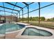 Relaxing screened-in pool and spa area with lush greenery in the background at 1735 Pine Ridge Dr, Davenport, FL 33896