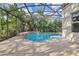 Sparkling in-ground pool with screened enclosure surrounded by lush landscaping and a concrete deck for relaxing and entertaining at 1827 Lindzlu St, Winter Garden, FL 34787