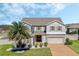 Beautiful two-story home featuring a brick driveway, stone accents, and a lush, green front yard with a palm tree at 1880 Bonser Rd, Minneola, FL 34715