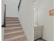 View of a carpeted staircase ascending past a half bathroom with a gray vanity and white walls at 1880 Bonser Rd, Minneola, FL 34715