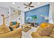 Comfortable living room with a ceiling fan, neutral-toned sofas, a blue accent wall, and staircase at 210 Vista Loop, Davenport, FL 33897