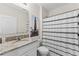Well-lit bathroom with a granite vanity, decorative mirror, and a shower with a stylish black and white curtain at 219 Meghan Cir, Deland, FL 32724