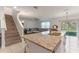 View of the kitchen island with granite countertops, a sink, and a breakfast bar, flowing into the living room and staircase at 219 Meghan Cir, Deland, FL 32724