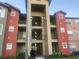 Multi-story condo building showing the balconies and colorful red and tan facade at 2207 Antigua Pl # 736, Kissimmee, FL 34741