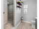 Bathroom featuring a tiled shower with a bench, a toilet, and a window with shelving at 2466 R E Byrd Rd, Frostproof, FL 33843