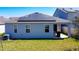 Back exterior view of the house featuring solar panels on the roof and a covered patio at 249 Hamlet Loop, Davenport, FL 33837