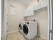 Efficient laundry room featuring modern washer and dryer, storage cabinets, and tile floors at 25 Lakeshore Blvd, St Cloud, FL 34769