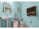 Quaint blue bathroom with a pedestal sink, a patterned toilet seat, and neatly arranged towels at 2933 White Cedar Cir, Kissimmee, FL 34741