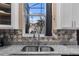 Close up of a stainless steel kitchen sink, granite counter tops and elegant backsplash at 2933 White Cedar Cir, Kissimmee, FL 34741