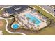 Aerial view of community pool area with palm trees, lounge chairs, clubhouse and a playground at 2984 Sanctuary Dr, Clermont, FL 34714