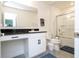 Bright bathroom featuring a vanity with dark countertop, toilet, and a shower-tub combo with glass doors at 2984 Sanctuary Dr, Clermont, FL 34714