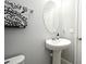 Cozy half bathroom featuring a pedestal sink, decorative mirror and stylish black and white towel at 3237 Palatka St, Orlando, FL 32824