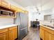 Well-lit kitchen features wood cabinets, stainless steel refrigerator, and an open view into the dining area at 3403 Greenwich Village Blvd # 104, Orlando, FL 32835