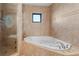 Bathroom featuring a jetted tub, glass shower, and tiled walls at 35624 Cypress Ct, Leesburg, FL 34788