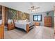 Spacious main bedroom with a nature scene mural, ceiling fan, and tile flooring at 35624 Cypress Ct, Leesburg, FL 34788