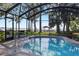 A screened-in pool area with a sparkling pool, offering views of the picturesque backyard and waterfront gazebo at 35624 Cypress Ct, Leesburg, FL 34788