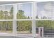 View from a window with white blinds, showcasing the lush greenery outside at 4192 Barbuda Ln, Kissimmee, FL 34758