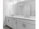 Bright bathroom featuring a double sink vanity with white cabinets, a large mirror and modern lighting at 4198 Barbuda Ln, Kissimmee, FL 34758