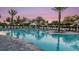 Community swimming pool at dusk, lined with lounge chairs and palm trees at 4198 Barbuda Ln, Kissimmee, FL 34758