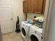 Functional laundry room with washer, dryer, storage space, and neutral tile flooring for added convenience at 4847 Lake Milly Dr, Orlando, FL 32839