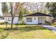 A charming one-story white house with a dark roof and a well-maintained lawn and beautiful trees at 5604 7Th Se St, Lakeland, FL 33812