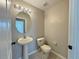 Half bath with neutral walls, tiled floor, pedestal sink, toilet, and vanity lighting at 607 Kissimmee Ln, Kissimmee, FL 34759