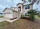 View of the two story home with a two car garage, manicured landscaping, and light pink exterior paint at 607 Kissimmee Ln, Kissimmee, FL 34759