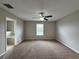 Bright main bedroom with neutral walls, plush carpeting, ceiling fan, and window that provides natural light at 607 Kissimmee Ln, Kissimmee, FL 34759