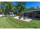Landscaped backyard with a screened in patio and stone fire pit surrounded by green grass and mature trees at 7614 Lake Dr, Belle Isle, FL 32809