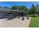 Backyard with a stone fire pit, screened in patio, grill, and green grass on a sunny day at 7614 Lake Dr, Belle Isle, FL 32809