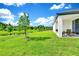 Large grassy backyard with patio, pond view, and mature tree offering a serene and picturesque outdoor space at 780 Livestock Loop, St Cloud, FL 34771