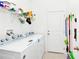 Well-organized laundry room featuring washer, dryer, storage shelves, and cleaning supplies, offering convenience and functionality at 780 Livestock Loop, St Cloud, FL 34771