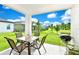 Relaxing covered patio features a table with seating and a grill, overlooking a lush lawn and picturesque pond at 780 Livestock Loop, St Cloud, FL 34771