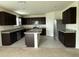 A spacious kitchen featuring dark cabinets, stainless steel appliances, and a center island with granite countertops at 124 Sofia Ln, Lake Alfred, FL 33850