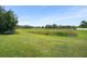 Scenic view of a vast green field with a small pond and scattered trees at 12824 Penshurst Ln, Windermere, FL 34786