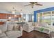Open-concept living room boasts wood floors, gray couches, and kitchen with stainless steel appliances at 12824 Penshurst Ln, Windermere, FL 34786