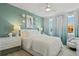 Serene bedroom with light teal accent wall, white bedding, and lots of natural light at 15567 Gentle Rain Dr # 194, Winter Garden, FL 34787