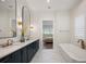 Bright bathroom featuring double vanity, soaking tub, and scenic views from the plantation shutters at 15847 Vetta Dr, Bella Collina, FL 34756