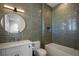Modern bathroom with light green tile, white cabinets, and a round mirror at 15847 Vetta Dr, Bella Collina, FL 34756
