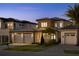 Exterior evening shot of a modern home with stone accents, a two-car garage, and manicured lawn at 15847 Vetta Dr, Bella Collina, FL 34756