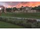 Beautiful Tuscan style architecture with a stone wall, green lawn, and sunset sky at 15847 Vetta Dr, Bella Collina, FL 34756