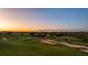 Panoramic aerial view of a meticulously maintained golf course at sunset, showcasing its lush green fairways at 15847 Vetta Dr, Bella Collina, FL 34756