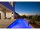 Backyard pool and patio with water feature, surrounded by plants and illuminated at twilight at 15847 Vetta Dr, Bella Collina, FL 34756