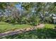 Lush backyard featuring a brick pathway, mature trees, and vibrant landscaping at 215 Forrest Dr, Sanford, FL 32773